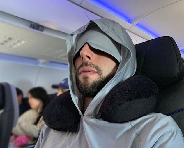 man with mustache and beard sleeping on a plane in a deep sleep hoodie